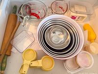 Drawer view showing nested metal bowls, plastic bowl, rolling pins, measuring sets, containers