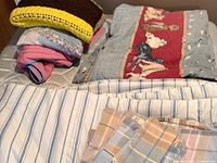 Stack showing quilts, crocheted throw and sheet set on mattress