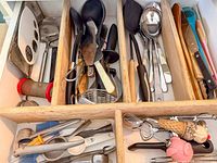 Drawer view showing mixed utensils including ladles, spatulas, whisks, mashers, novelty scoop