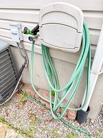 Full view of green hose coiled on wall mount