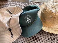 Three hats side by side: Columbia bucket, Gananoque cap, straw hat