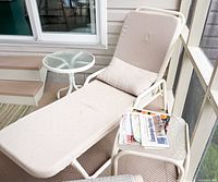 Chaise lounge with cushion, round side table, and square side table shown together