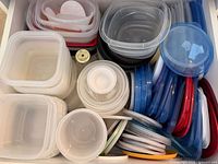 Drawer filled with assorted clear plastic containers and colourful lids