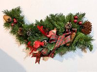 Artificial pine garland swag decorated with plaid ribbon, pinecones, red berries, red birds
