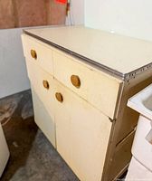 Full view of off-white cabinet showing drawers, doors, metal trim