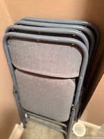 Four folded metal chairs leaning against wall
