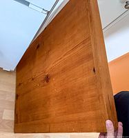 Full view of solid wood tabletop leaning vertically showing surface and edges