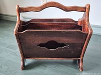 Front view of wooden magazine rack showing scalloped rail and cut-out panel