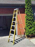 Full view of 8 ft yellow fiberglass step ladder set up outdoors