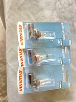 Three sealed Sylvania Basic 9005 halogen headlight bulbs on blister cards