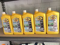 Five yellow Pennzoil Platinum 0W-20 motor oil bottles on shelf
