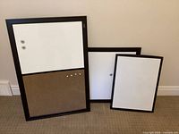Three framed boards standing against wall