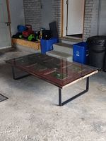 Full view of coffee table in garage showing glass top and metal legs