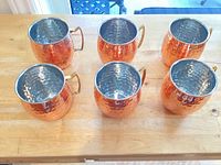 Top view of six hammered copper mugs showing interior stainless finish