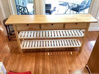 Full view of pine console table with three drawers and two slatted shelves