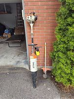 STIHL powerhead with blower tube, trimmer attachment leaning nearby