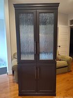 Front view of closed cabinet showing two glass upper doors and two solid lower doors