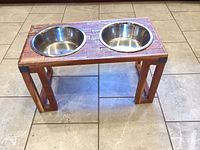 Front angled view of wooden feeding station with two stainless bowls
