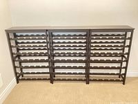 Front view of three assembled wood wine racks with scalloped shelves
