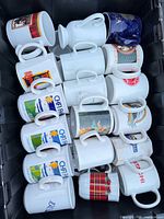 Top view of tote containing multiple rows of assorted white and colored printed mugs