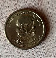 Obverse of John Quincy Adams $1 coin showing portrait and inscriptions