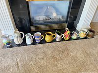 All ten pitchers lined on fireplace hearth