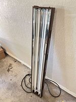 Full view of brown fluorescent shop light with four tubes and power cord