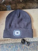 Full view of black knit beanie showing LED light on cuff