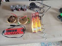 All items laid out: 3 gel fuel cans, air pump, inverter, spiral anchor, brass covers, match boxes