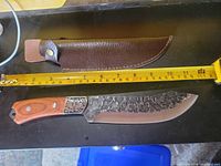 Knife, tape measure showing 12 in blade, sheath above
