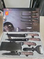 Open box showing all knives, scissors, peeler seated in tray with printed lid diagram