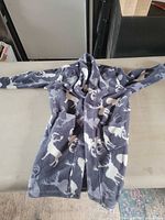 Full view of gray and white deer print fleece robe laid flat showing front pockets and belt loops