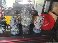 All three owl statues grouped together showing relative sizes and colours