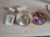 Tin, lid, partial card deck and six dice laid out