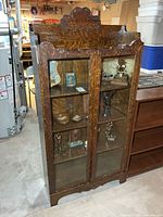 Front view of oak bookcase with glass doors and carved crest