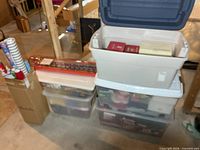 Stacked plastic totes, tall box of wrapping paper rolls and additional long package on top