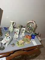 group shot showing marble elephant, Belleek vase, Lladro dog, floral basket, wall pockets, Blue Mountain elephant, plates and additional figurines
