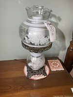 Full view of one lamp showing shade, chimney, glass font with etched roses, metal base
