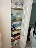 Full view of linen closet shelves showing towels, sheets, boxed heated mattress pad