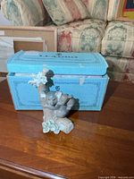Front view of figurine beside Lladro box