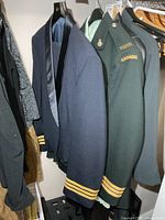 Green Canadian military service jacket and navy mess jacket on hangers