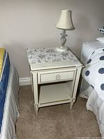 Front view of Baronet nightstand beside bed, lamp on top
