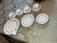 Stack of dinner plates, stack of side plates, four cups with saucers