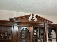 Overview of cabinet top shelf with silver-plated dishes inside