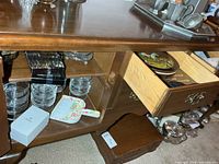 View of buffet interior: stacked glass dishes, coasters, crumb brush, boxes