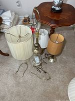 Three lamps, shades, harps and cords on carpet
