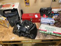 Workbench surface showing radio, red toolbox, tool bags and boxed items
