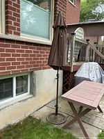 Umbrella closed on stand beside house showing base and pole