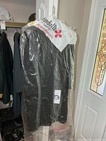 Coat hanging in dry-cleaner plastic showing overall length and texture