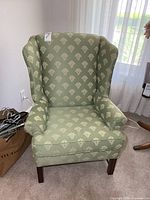 Front view of green wing back chair, shows upholstery pattern and overall condition